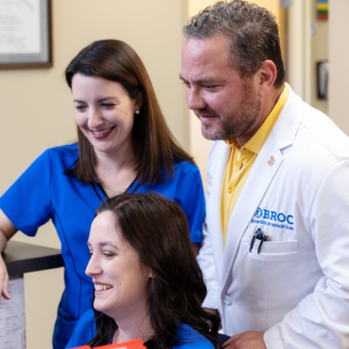 Dr. Riche and his staff smiling at a computer screen